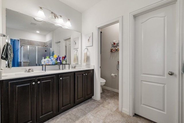 bathroom with tile patterned floors, vanity, toilet, and a shower with shower door