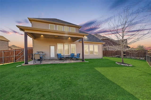 back house at dusk with a patio and a yard