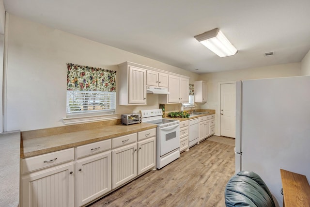 kitchen with sink, white appliances, light hardwood / wood-style flooring, and white cabinets