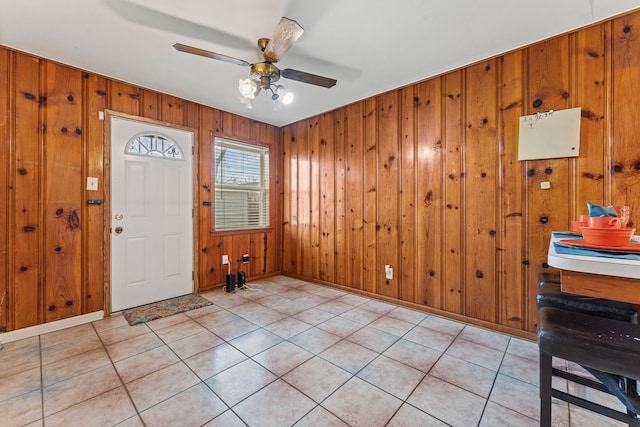 tiled entryway featuring ceiling fan and wood walls