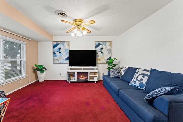 living room with ceiling fan, carpet flooring, and a textured ceiling