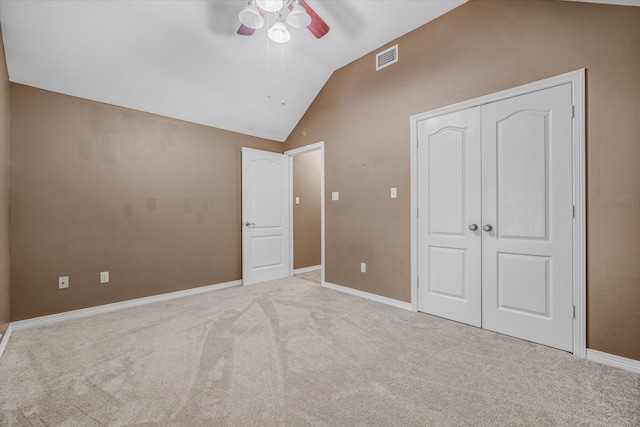 unfurnished bedroom featuring ceiling fan, light colored carpet, lofted ceiling, and a closet