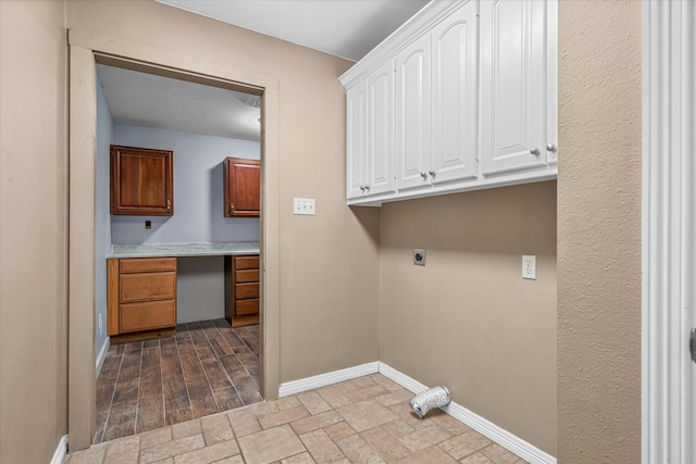 laundry area with electric dryer hookup and cabinets