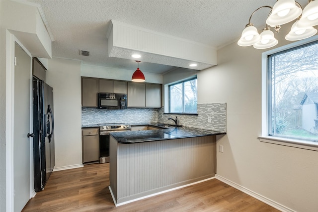 kitchen with pendant lighting, sink, wood-type flooring, black appliances, and kitchen peninsula