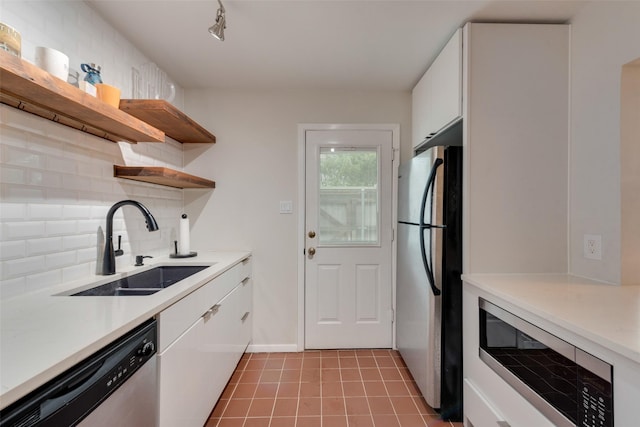 kitchen with sink, backsplash, stainless steel appliances, white cabinets, and light tile patterned flooring