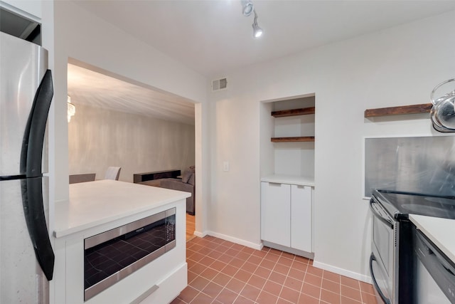 kitchen with light tile patterned floors, stainless steel appliances, and white cabinets