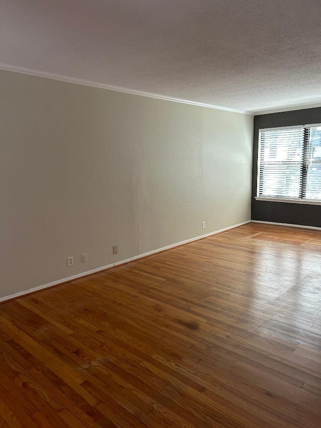 unfurnished room featuring hardwood / wood-style floors, ornamental molding, and a textured ceiling