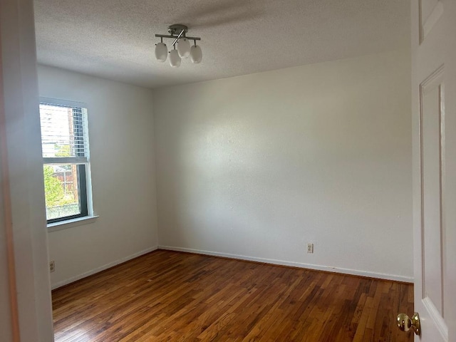 spare room with dark wood-type flooring and a textured ceiling