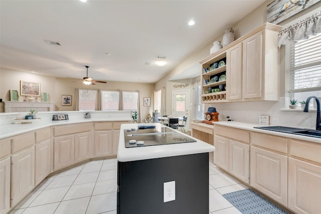 kitchen featuring light tile patterned flooring, sink, plenty of natural light, an island with sink, and black electric stovetop