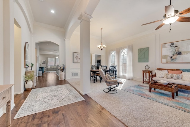 living room with ornate columns, dark wood-type flooring, and ceiling fan with notable chandelier