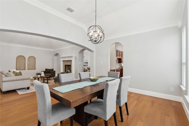 dining room with ornamental molding, light hardwood / wood-style floors, and a chandelier