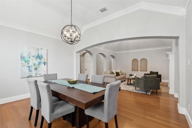 dining room featuring a notable chandelier, crown molding, light hardwood / wood-style flooring, and vaulted ceiling