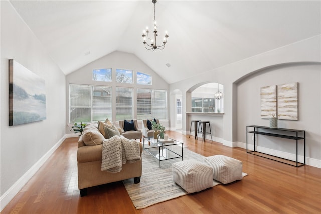 living room with wood-type flooring, high vaulted ceiling, and an inviting chandelier