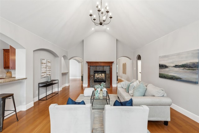 living room featuring an inviting chandelier, lofted ceiling, a fireplace, and light wood-type flooring