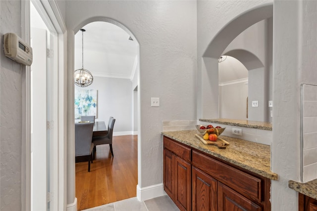 bathroom with a notable chandelier, ornamental molding, hardwood / wood-style floors, and vanity