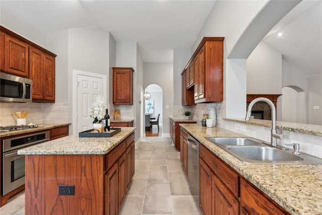 kitchen featuring sink, light stone countertops, a center island, and appliances with stainless steel finishes