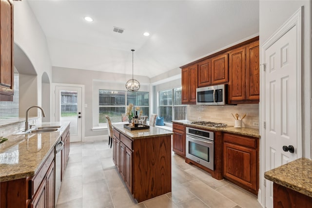 kitchen with a kitchen island, sink, backsplash, hanging light fixtures, and stainless steel appliances