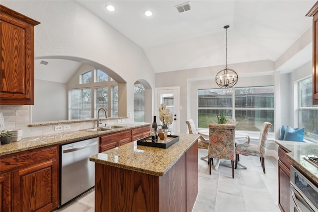 kitchen with lofted ceiling, sink, decorative light fixtures, appliances with stainless steel finishes, and backsplash