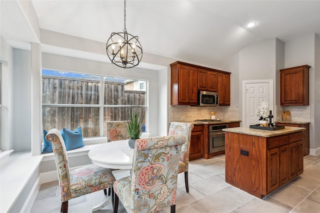 kitchen featuring pendant lighting, stainless steel appliances, a center island, light stone counters, and decorative backsplash