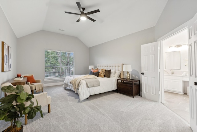 bedroom featuring ceiling fan, light colored carpet, vaulted ceiling, and ensuite bath