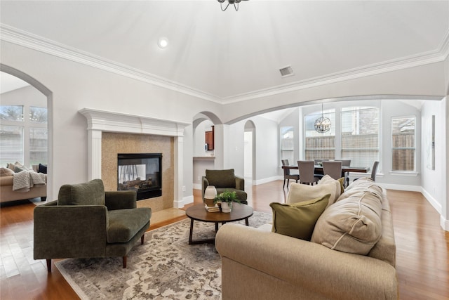 living room with a tiled fireplace, crown molding, plenty of natural light, and hardwood / wood-style floors