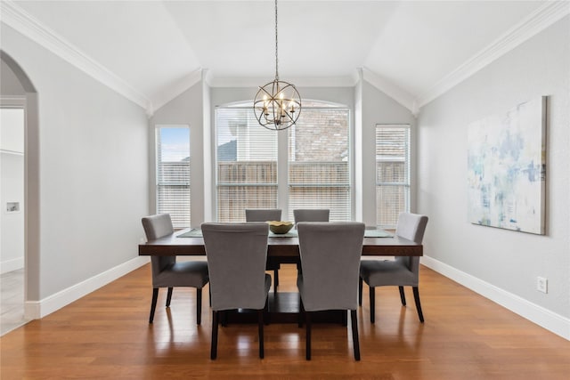 dining room with hardwood / wood-style floors, crown molding, and vaulted ceiling