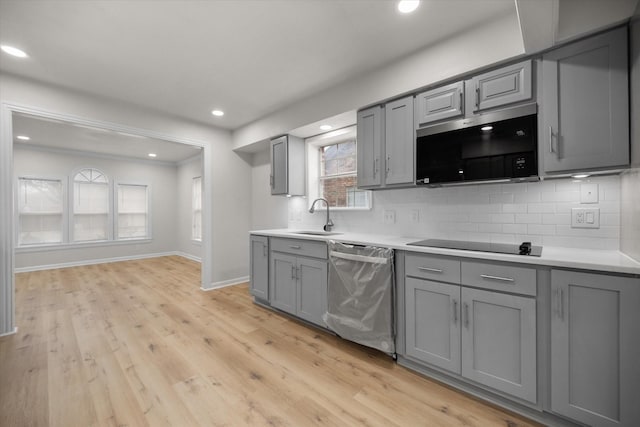 kitchen featuring sink, light hardwood / wood-style flooring, gray cabinets, appliances with stainless steel finishes, and backsplash