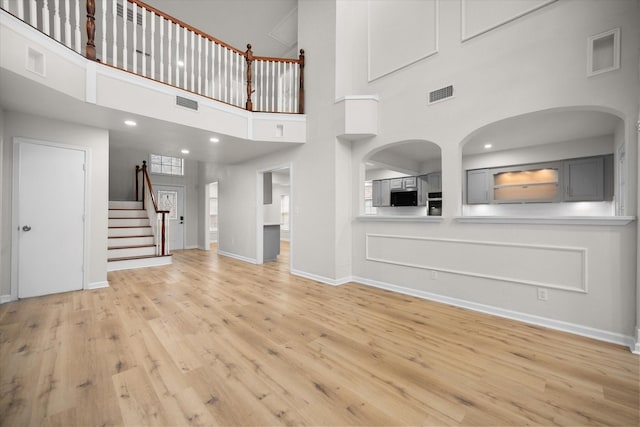 unfurnished living room featuring light hardwood / wood-style flooring and a high ceiling