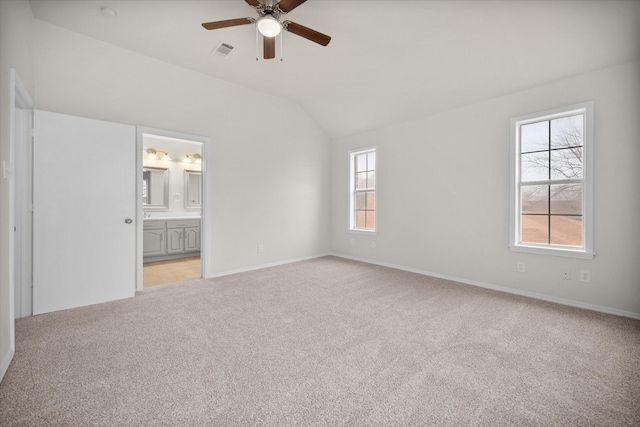 unfurnished bedroom featuring lofted ceiling, light colored carpet, connected bathroom, and ceiling fan