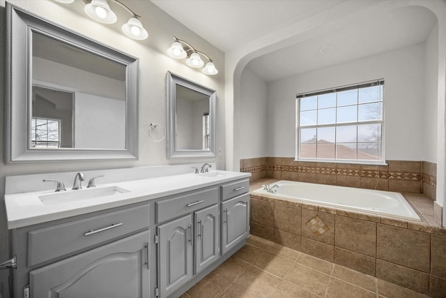 bathroom with a relaxing tiled tub, tile patterned floors, and vanity