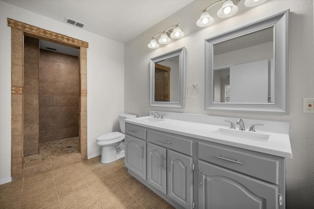 bathroom with vanity, a tile shower, and toilet