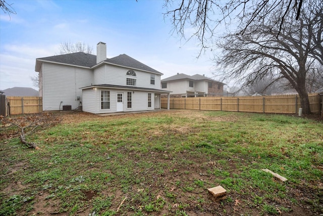 rear view of property featuring central AC and a lawn