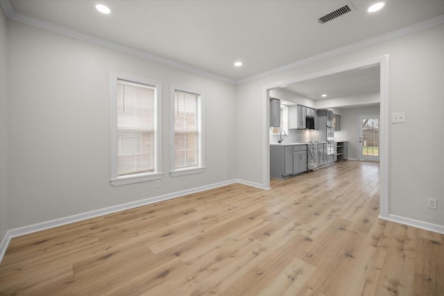 unfurnished living room featuring crown molding, sink, and light hardwood / wood-style flooring