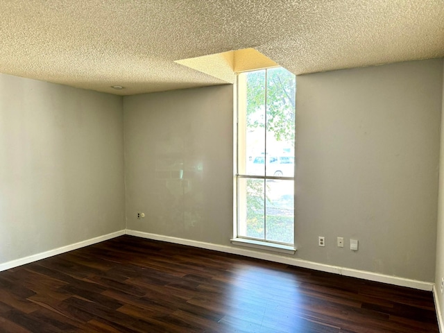 empty room featuring plenty of natural light, dark hardwood / wood-style floors, and a textured ceiling