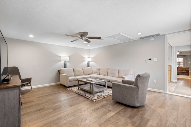 living room with ceiling fan, light hardwood / wood-style floors, and a textured ceiling