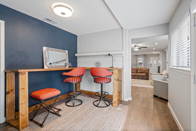 sitting room with hardwood / wood-style flooring, indoor bar, plenty of natural light, and ceiling fan