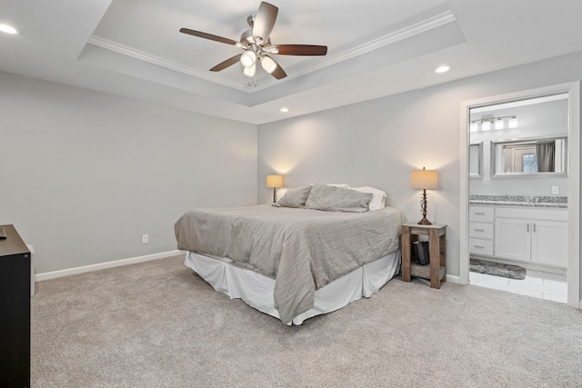 carpeted bedroom with ensuite bath, ornamental molding, and a raised ceiling