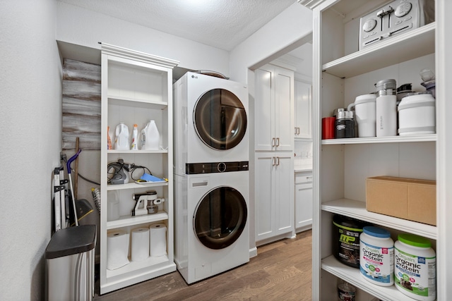 washroom with stacked washer / dryer, dark hardwood / wood-style floors, and a textured ceiling