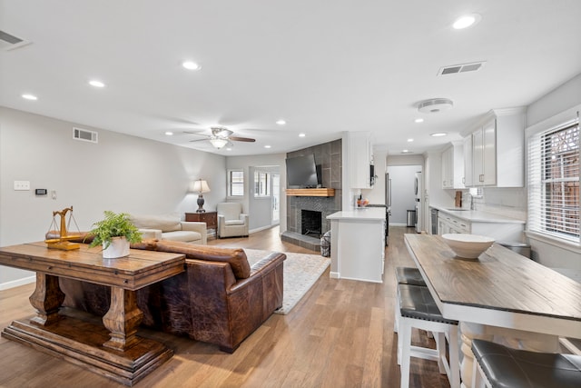 living room featuring a healthy amount of sunlight, sink, a fireplace, and light hardwood / wood-style floors