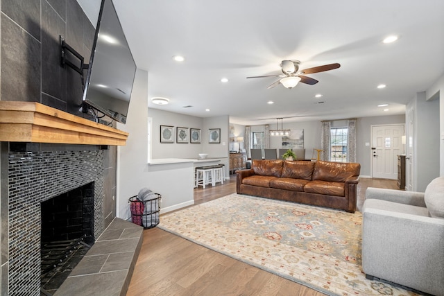 living room with ceiling fan, a tiled fireplace, and hardwood / wood-style floors