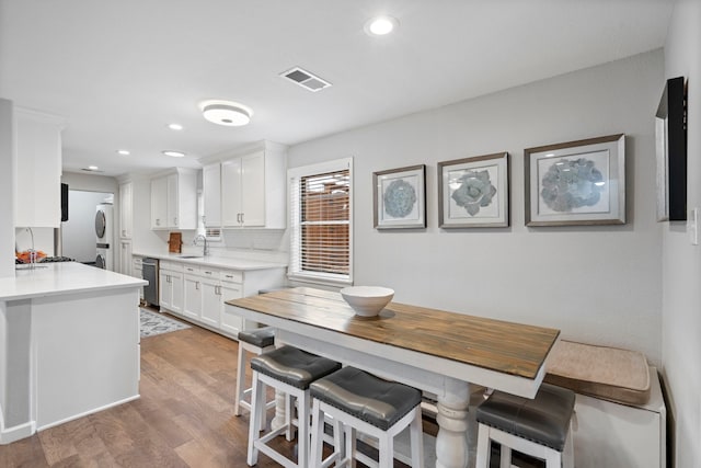 kitchen with hardwood / wood-style flooring, white cabinetry, tasteful backsplash, and a breakfast bar area