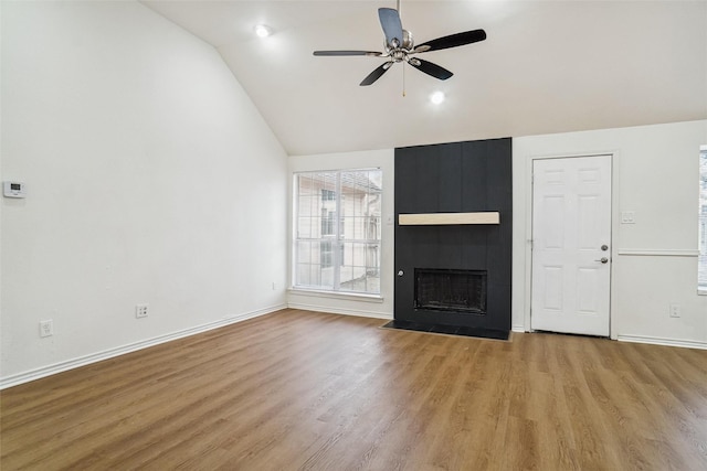 unfurnished living room with ceiling fan, a large fireplace, vaulted ceiling, and light hardwood / wood-style flooring