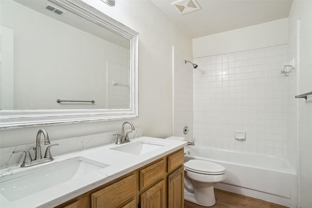 full bathroom featuring hardwood / wood-style flooring, vanity, tiled shower / bath, and toilet