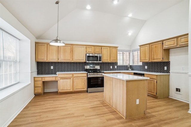 kitchen with hanging light fixtures, appliances with stainless steel finishes, a center island, and light wood-type flooring