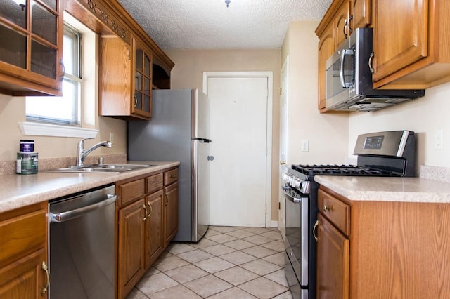 kitchen featuring sink, light tile patterned flooring, a textured ceiling, and appliances with stainless steel finishes