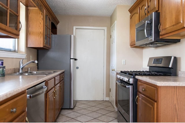 kitchen featuring appliances with stainless steel finishes, sink, a textured ceiling, and light tile patterned floors