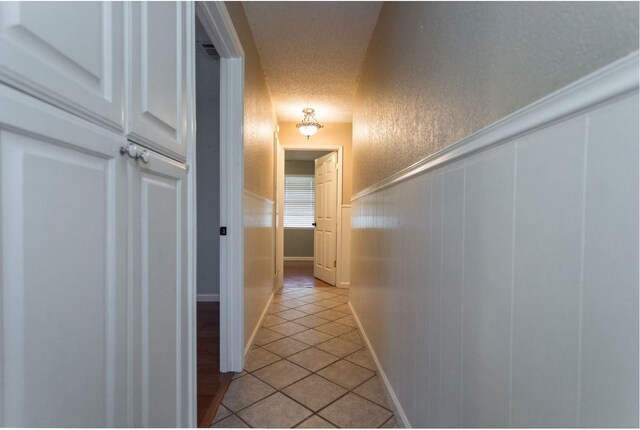 hallway with light tile patterned flooring and a textured ceiling