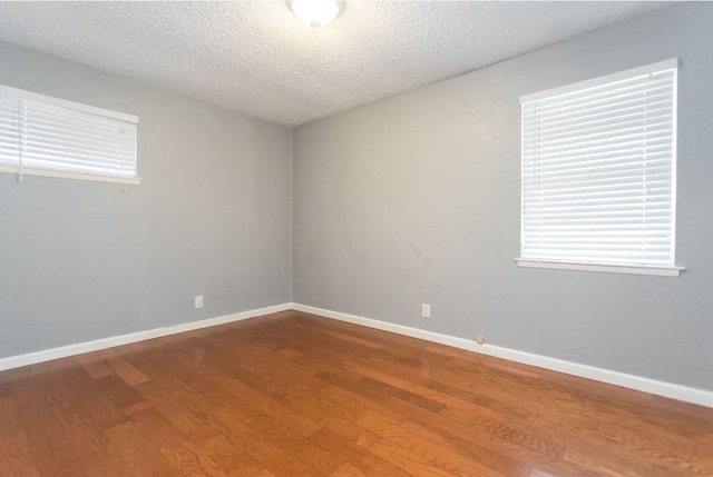 empty room with wood-type flooring and a textured ceiling