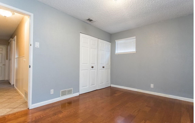 unfurnished bedroom with hardwood / wood-style flooring, a closet, and a textured ceiling