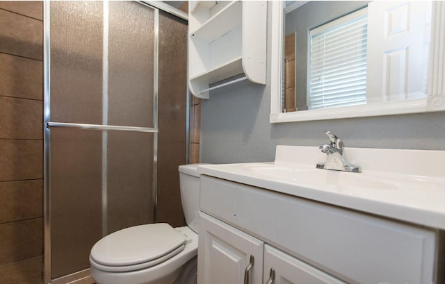 bathroom with an enclosed shower, vanity, and toilet